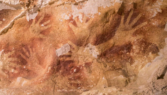 Трафаретные изображения рук за тысячи лет покрылись слоями наростов-сталактитов (фото Maxime Aubert, Griffith University, Australia).